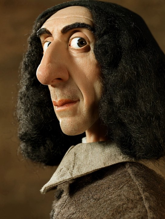 An animated portrait of Benedict de Spinoza, with dark shoulder-length curls and a pale collar against a warm brown background.